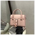 Detail of pink leather handbag showing silver buckle, top handle and matching shoulder strap - Pink