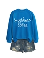 Detail view of the sunshine and coffee print on the blue sweatshirt and denim shorts - Lake Blue (White Font)
