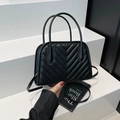 Piccola borsa a mano nera con trapuntatura a V, doppi manici e tracolla su sfondo bianco - Nero