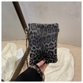 Detalle del bolso bandolera mini de leopardo con cadena dorada sostenido a mano - Negro