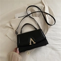 Elegante borsa a tracolla in pelle nera con fibbia a V dorata su blazer bianco - Nero