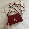 Borsa a tracolla rosso scuro con chiusura a V dorata su sfondo blazer beige crema - Rosso