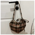 Nahaufnahme der herzförmigen Wolltasche mit Karomuster und Schleifendetail an weißer Tür - Braun