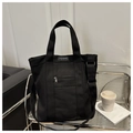 Detalle macro del bolso de lona negra con correa ajustable y bolsillo con cremallera - Negro