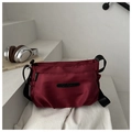 Dettaglio della borsa a tracolla in nylon bordeaux con tasche in un contesto lifestyle - Rosso