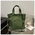Primer plano de un bolso tote de lona verde con cremallera de metal y etiqueta de moda - Verde