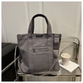 Detalle de bolso tote de lona gris con bolsillo frontal y parche con logotipo de moda - Gris