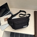 Versatile black nylon crossbody chest bag for men placed next to a laptop on desk - Black