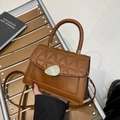 Brown crocodile texture handbag with diamond stitching and gold metal clasp on a wooden bench - Brown