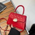 Sac à main en cuir rouge avec motif crocodile et fermoir doré, présenté par un mannequin - Rouge