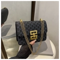 Bolso bandolera negro con diseño de letras M y cadena dorada reflejado en un espejo chic - Negro