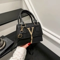 Schicke schwarze Handtasche mit Pailletten, goldenem V-Akzent und Quasten-Detail im Halten - Schwarz