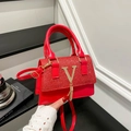 Rote Umhängetasche mit Paillettenklappe, goldenem V-Logo und Quaste auf schwarzem Tisch - Rot