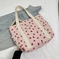 Pink corduroy tote bag featuring red strawberry prints and white woven handles - Pink