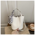 Nahaufnahme der weißen Leder-Eimertasche mit Lychee-Textur und dekorativem gepunktetem Schal - Weiß