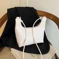 Minimalist cream white lychee texture shoulder bag with knotted strap on wooden chair - Off White
