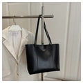 Detalle de un bolso tote de cuero negro con letras doradas y textura de grano natural - Negro