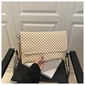 Close-up of cream envelope clutch bag with red geometric pattern and wrist strap - Monogram Khaki