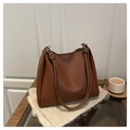 Detalle de bolso tote de cuero sintético marrón con asas anudadas sobre manta beige suave - Marrón