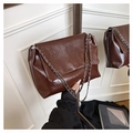 Detailed shot of dark brown wrinkled leather texture and silver chain strap on a tote bag - Brown