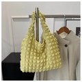 Detail of light yellow popcorn texture tote bag hanging next to a beige trench coat - Bean Green
