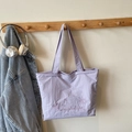 Lavender textured tote bag with star embroidery hanging next to a denim jacket - Purple