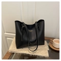 Primer plano detallado de un bolso tote de cuero negro con grano fino y logo dorado en bufanda - Negro