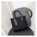 Detail of black faux shearling tote bag featuring leather handles and fashion logo tag - Black