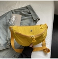 Detail shot of bright yellow nylon half-moon bag with circular metal logo and triangle zipper - Yellow