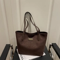 Bolso tote de ante marrón con etiqueta de moda sobre una silla negra minimalista - Marrón