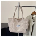 Detail der beigen Canvas-Tragetasche mit blauer TGT-Stickerei und robustem Stoffgriff - Khaki