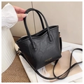 Detail der schwarzen Bucket Bag aus genarbtem Leder mit goldener Aufschrift im Raum - Schwarz