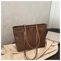 Detalle de bolso tote de cuero marrón oscuro con abrigo beige y libro decorativo - Marrón