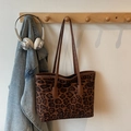 Grande borsa tote leopardata con manici in pelle marrone su un gancio di legno - Marrone