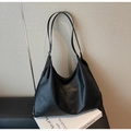 Detailed view of matte black leather tote bag with slender straps on a minimal desk - Black