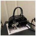 Detail of glossy black patent leather Boston bag with decorative pearl bow charm - Black