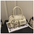 Detail of cream Boston bag featuring beaded bow charm and smooth leather texture - White