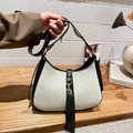Détail du sac hobo avec bordure noire contrastée et fermoir en métal doré sur table en bois - Blanc
