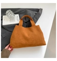 Vue détaillée du sac seau minimaliste en daim orange avec livre d'art et blazer - Marron