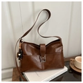 Nahaufnahme der braunen Retro-Ledertasche mit Holzperlen-Anhänger auf einem weißen Buch - Braun mit Anhänger