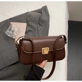 Dettaglio della borsa vintage marrone con chiusura dorata su sfondo di abito grigio - Marrone