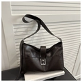 Détail d'un sac à main en cuir marron foncé avec boucle argentée sur des livres - Style Without Charm / Marron