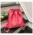 Close-up of pink drawstring backpack with smooth nylon texture on minimalist stairs - Rose Red
