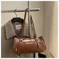 Detail der dunkelbraunen Schultertasche aus Wachsleder mit Metallschnallen am Mantel - Hellbraun