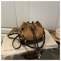 Brown bucket bag featuring suede contrast and woven handle in lifestyle setting - Brown