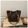 Detail of dark brown leather tote with plush dog charm on a soft knit blanket - Coffee With Pendant