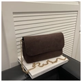 Detail of dark brown suede shoulder bag featuring a thick gold chain strap on a white stand - Brown