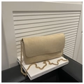 Detail of beige suede flap bag featuring elegant gold chain strap on a white book decor - Khaki