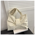 Dettaglio ravvicinato di una borsa tote color panna in similpelle a forma di fiocco - Bianco