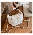 Close-up of white quilted mini bag with gold camellia clasp on wooden surface - White